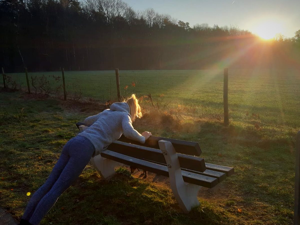 Iemand doet opdrukoefeningen tegen een picknickbank
