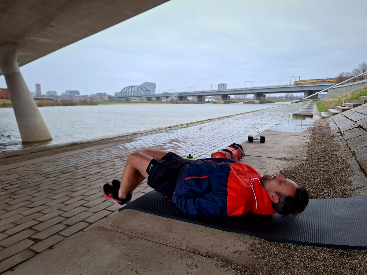 Iemand doet een buikspieroefening op een mat aan de rivier